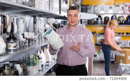 Positive male customer is holding blender in appliances store Positive male customer is holding blender in appliances store 72804066