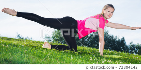 Woman in pink T-shirt is practicing yoga 72804142