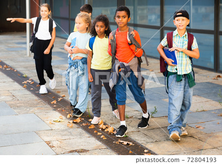 Smiling tweenagers walking outside school building on autumn day Smiling tweenagers walking outside school building on autumn day 72804193