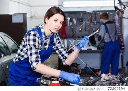 Young woman master is choosing instruments for work in workshop. Young woman master is choosing instruments for work in workshop. 72804194