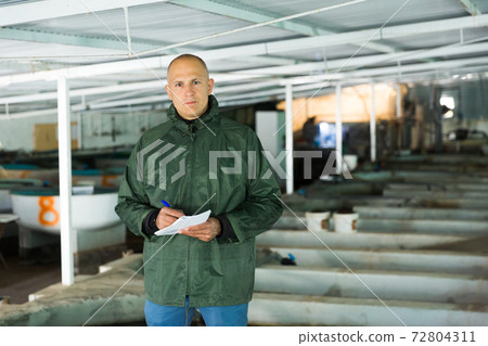 Man inspecting tanks for rearing trout fry Man inspecting tanks for rearing trout fry 72804311