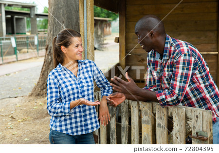 Woman and man chatting near stable 72804395