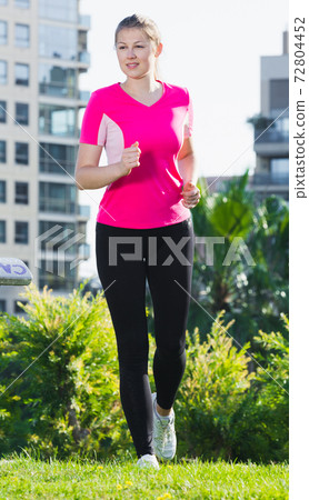 Smiling adult woman in pink T-shirt is running Smiling adult woman in pink T-shirt is running 72804452