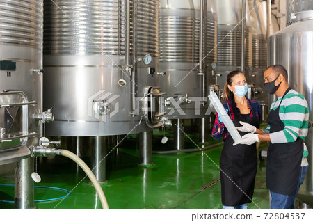 Man and woman in protective mask with beaker in winery shop 72804537