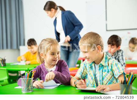 Portrait of schoolchildren sitting in classroom and chatting during lesson Portrait of schoolchildren sitting in classroom and chatting during lesson 72804539