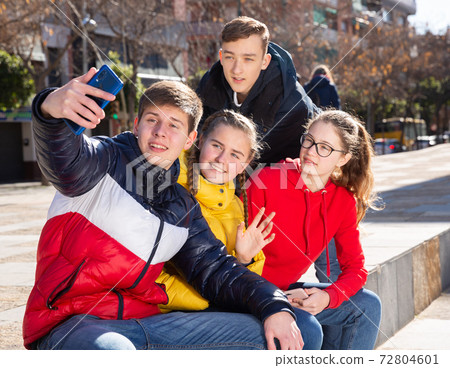 Joyful teens take group selfie on street Joyful teens take group selfie on street 72804601