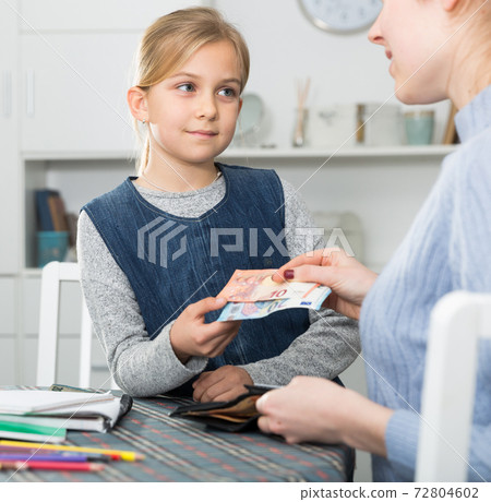 Mom gives money to little schoolgirl Mom gives money to little schoolgirl 72804602