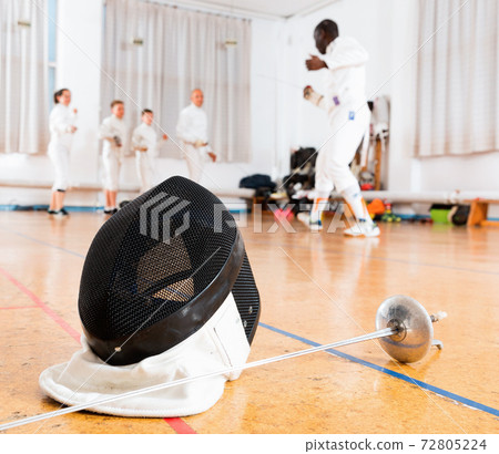 Closeup of fencing mask and rapier on floor in gym Closeup of fencing mask and rapier on floor in gym 72805224