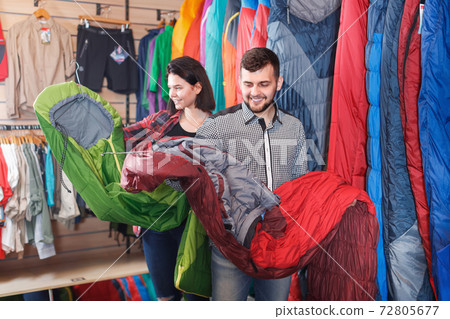 Positive family couple choosing new sleeping bags Positive family couple choosing new sleeping bags 72805677