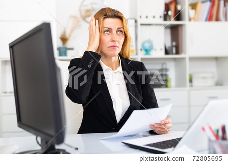 Frustrated woman working alone in office Frustrated woman working alone in office 72805695