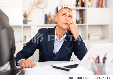 Upset young businessman working documents and laptop Upset young businessman working documents and laptop 72805715