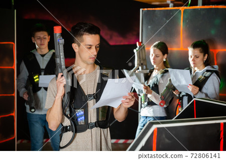 Young man reading rules before playing lasertag Young man reading rules before playing lasertag 72806141