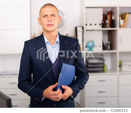 Young businessman standing in office while working day Young businessman standing in office while working day 72806525