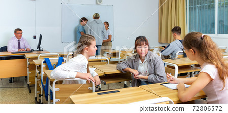 Positive students are talking about homework at desk 72806572