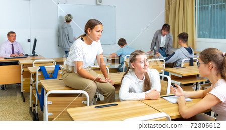 Girl and boy are sitting at the desk and talking about life in classroom. 72806612