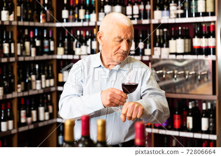 Portrait of senior man tasting red wine at wine shop Portrait of senior man tasting red wine at wine shop 72806664