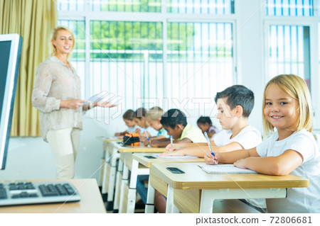 Side view of schoolkids group working on lecture in classroom Side view of schoolkids group working on lecture in classroom 72806681
