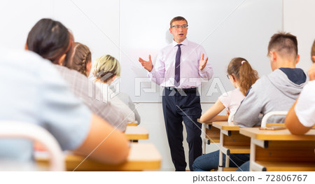 Male teacher lecturing to students at classroom Male teacher lecturing to students at classroom 72806767