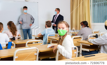 Teenage schoolgirl in protective mask during lesson in college Teenage schoolgirl in protective mask during lesson in college 72806778