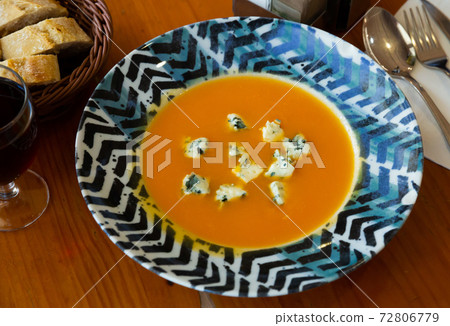 Carrot cream soup with gorgonzola at plate on table 72806779