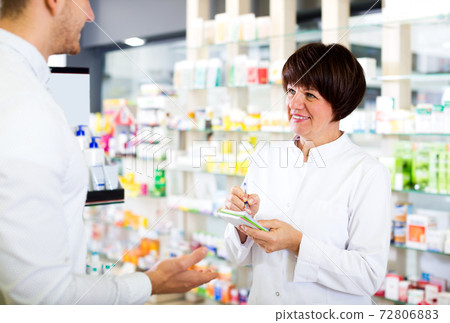 Woman druggist wearing white coat Woman druggist wearing white coat 72806883