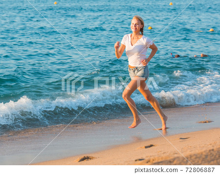 Sportswoman is jogging on the beach 72806887