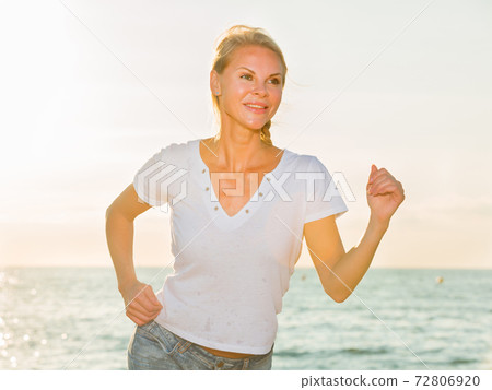 Female in white T-shirt is jogging 72806920