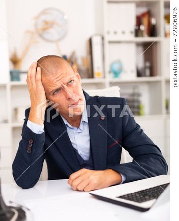 Upset man working with laptop and papers Upset man working with laptop and papers 72806926
