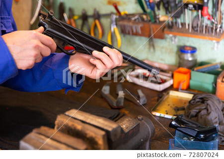 Disassembled smallbore sporting pistol in hands of gunsmith Disassembled smallbore sporting pistol in hands of gunsmith 72807024