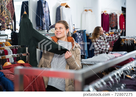 Woman choosing new overcoat in store 72807275