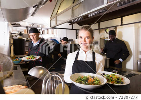 Waitress in restaurant kitchen with ordered meals 72807277
