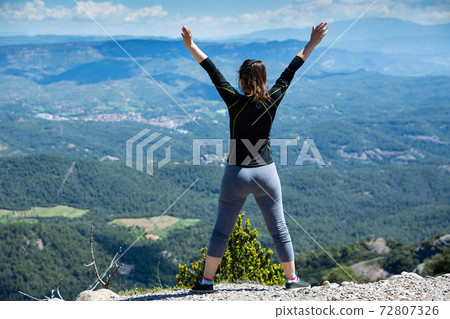 Rear view of female with raised hands on top of mountain Rear view of female with raised hands on top of mountain 72807326