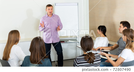 Man reading out report to colleagues 72807490