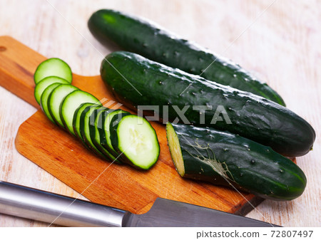 Cut fresh cucumbers on wooden table in home kitchen Cut fresh cucumbers on wooden table in home kitchen 72807497
