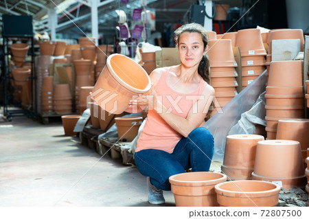 Woman chooses pots clay pots in store warehouse Woman chooses pots clay pots in store warehouse 72807500