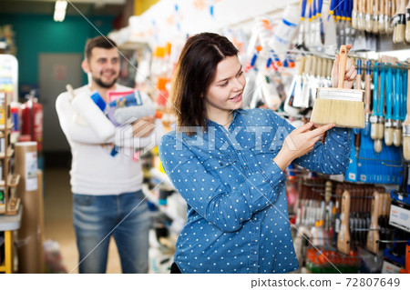 Couple examining various painting brushes Couple examining various painting brushes 72807649