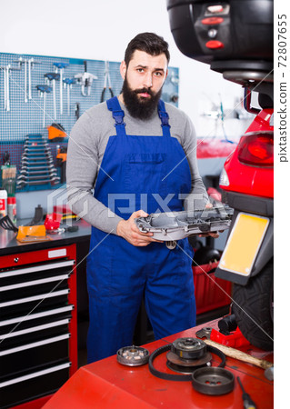 friendly man worker working at restoring motorbike in workshop 72807655