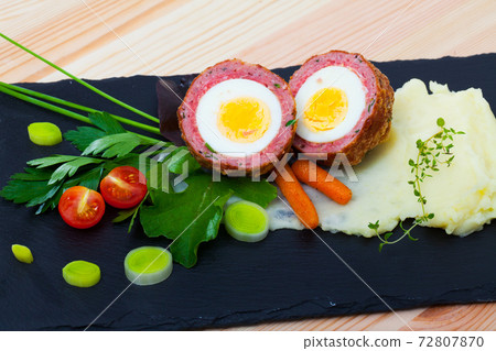 Dishes of traditional Scottish cuisine of scotch egg served with greens and potatoes 72807870