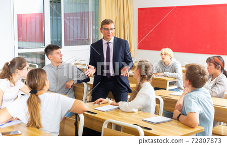 Teacher communicates freely with students in classroom at school Teacher communicates freely with students in classroom at school 72807873