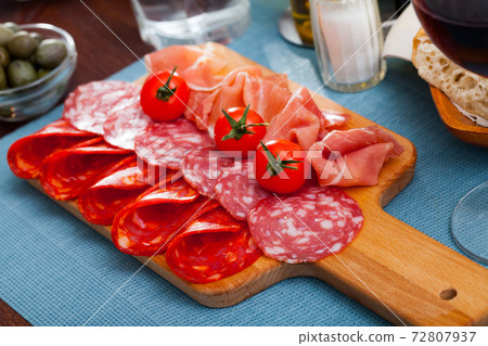 Spanish tapas - slicing sausages and jamon served on wooden board Spanish tapas - slicing sausages and jamon served on wooden board 72807937