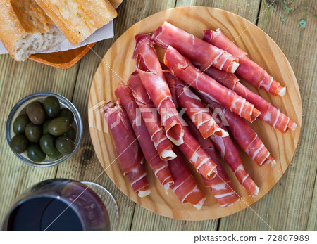 Spanish tapas - rolls of jamon serrano served on wooden board Spanish tapas - rolls of jamon serrano served on wooden board 72807989