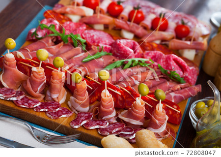 Spanish tasty meal slicing sausages and ham with cherry tomatoes and olives Spanish tasty meal slicing sausages and ham with cherry tomatoes and olives 72808047
