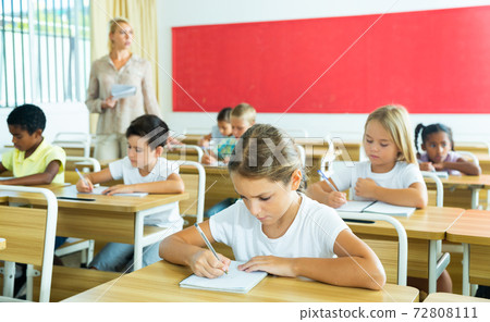 Focused tween schoolgirl writing in workbook during lesson Focused tween schoolgirl writing in workbook during lesson 72808111