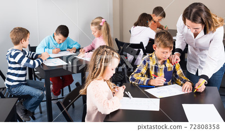 Little friendly children with teacher drawing in classroom Little friendly children with teacher drawing in classroom 72808358