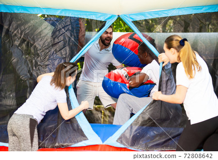 Adult fun friends box in huge boxing gloves in an amusement park 72808642