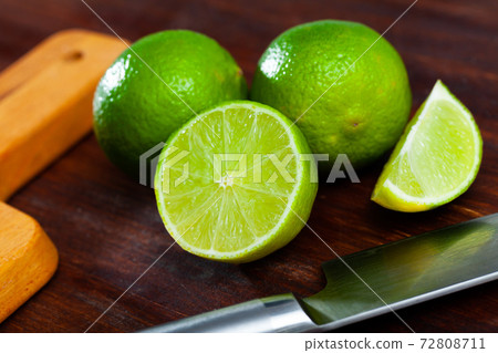 Whole and sliced limes on wooden table 72808711
