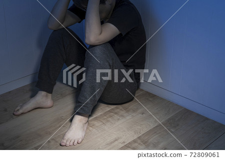 一個男人坐在一個黑暗的房間的地板上 72809061