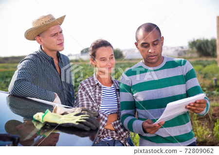 Farmers discussing papers near car on farm Farmers discussing papers near car on farm 72809062
