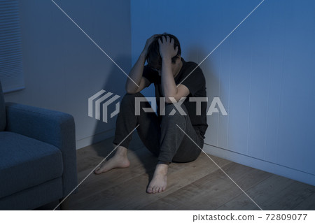 一個男人坐在一個黑暗的房間的地板上 一個男人坐在一個黑暗的房間的地板上 72809077