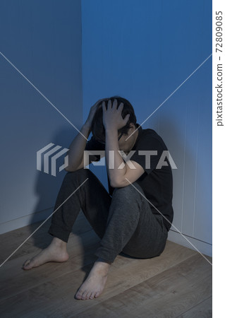 一個男人坐在一個黑暗的房間的地板上 72809085